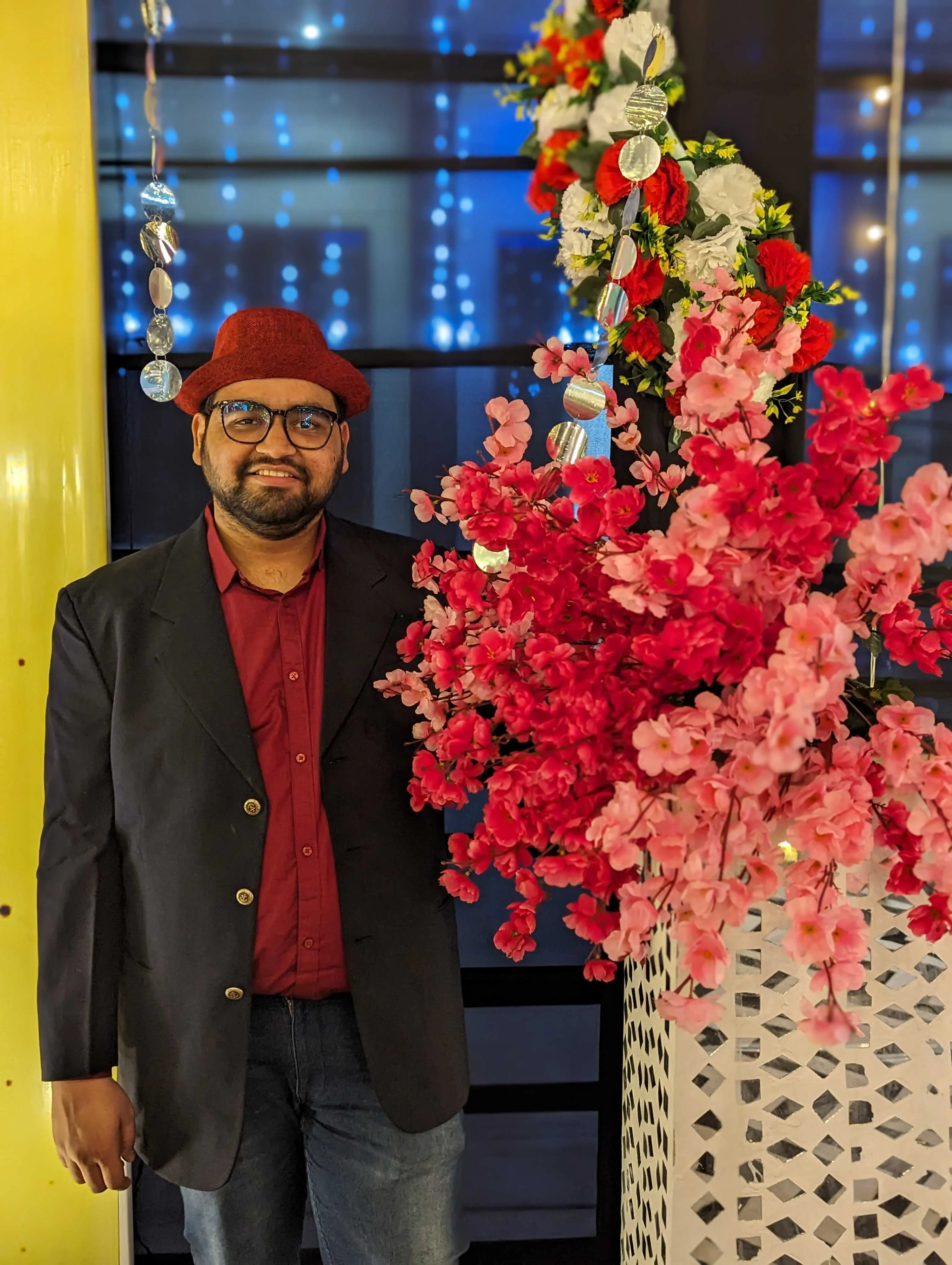 In a blazer and beanie at an evening event beside a flower arrangement